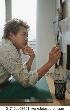 Man at desk reading notes View Large Photo Image Stock Image - Man at desk reading notes. Fotosearch