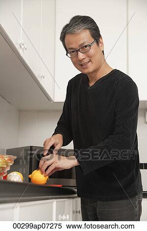 Man in kitchen cutting lemon, looking at camera and smiling View Large Photo Image Stock Photography - Man in kitchen cutting lemon, looking at camera and smiling. Fotosearch