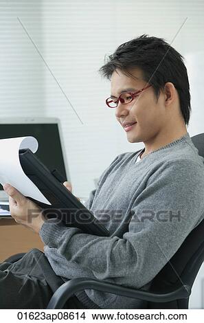 Man in office chair writing on clipboard View Large Photo Image Picture - Man in office chair writing on clipboard. Fotosearch