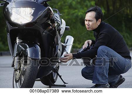 Stock Photo - Man looking at motorcycle. Fotosearch