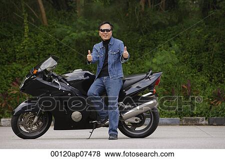 Man sitting on motorcycle, giving thumbs up View Large Photo Image Stock Photo - Man sitting on motorcycle, giving thumbs up. Fotosearch
