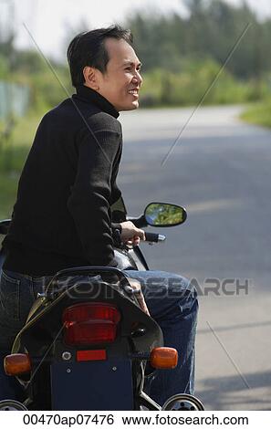 Man sitting on Motorcycle, looking away View Large Photo Image Stock Photograph - Man sitting on Motorcycle, looking away. Fotosearch