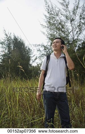 Stock Photograph - Man talking on mobile phone, hiking, outdoors. Fotosearch