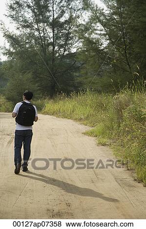 Man walking down dirt road, hiking, back to camera View Large Photo Image Stock Photo - Man walking down dirt road, hiking, back to camera. Fotosearch