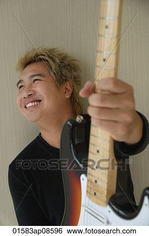 Man with guitar smiling and looking into distance View Large Photo Image Stock Photograph - Man with guitar smiling and looking into distance. Fotosearch