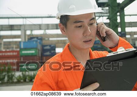 Man with hard helmet looking at clipboard View Large Photo Image Stock Photo - Man with hard helmet looking at clipboard. Fotosearch