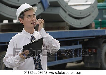 Man with hard helmet speaking into walkie talkie View Large Photo Image Stock Image - Man with hard helmet speaking into walkie talkie. Fotosearch