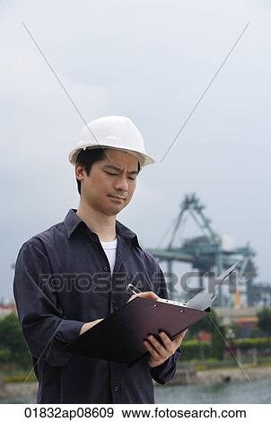 Man with hard helmet writing on clipboard View Large Photo Image Stock Photo - Man with hard helmet writing on clipboard. Fotosearch