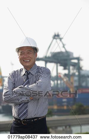 Stock Photo - Man with helmet and arms crossed, looking at camera. Fotosearch