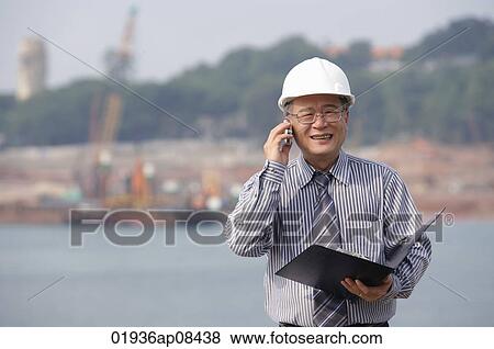 Stock Photo - Man with helmet, talking on the phone. Fotosearch