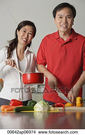 Mature couple in kitchen, preparing a meal together, smiling at camera View Large Photo Image Picture - Mature couple in kitchen, preparing a meal together, smiling at camera. Fotosearch