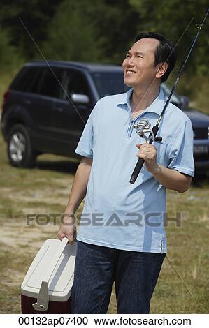 Mature man holding fishing pole and cooler, smiling View Large Photo Image Stock Image - Mature man holding fishing pole and cooler, smiling. Fotosearch