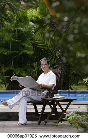 Mature man sitting by swimming pool, reading newspaper View Large Photo Image Stock Photography - Mature man sitting by swimming pool, reading newspaper. Fotosearch