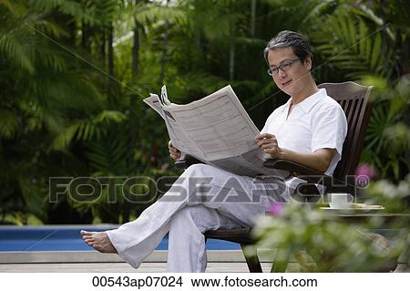 Mature man sitting outdoors, reading newspaper View Large Photo Image Picture - Mature man sitting outdoors, reading newspaper. Fotosearch