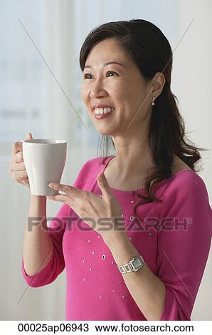 Mature woman holding cup, smiling, looking away View Large Photo Image Stock Image - Mature woman holding cup, smiling, looking away. Fotosearch