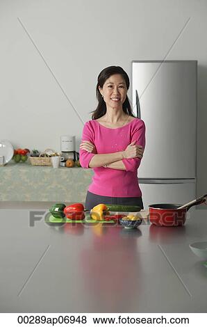 Mature woman in kitchen, arms crossed, looking at camera View Large Photo Image Stock Photo - Mature woman in kitchen, arms crossed, looking at camera. Fotosearch