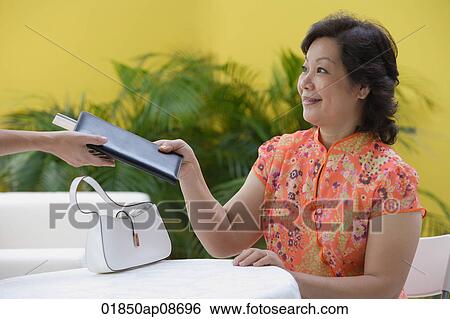 Mature woman in restaurant being handed bill View Large Photo Image Stock Photograph - Mature woman in restaurant being handed bill. Fotosearch