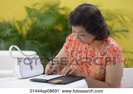 Mature woman in restaurant paying bill View Large Photo Image Stock Photo - Mature woman in restaurant paying bill. Fotosearch