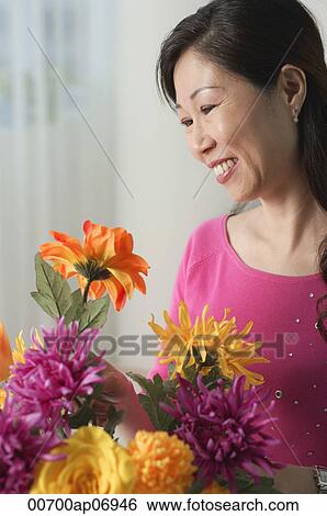 Mature woman looking at flowers, smiling View Large Photo Image Stock Photograph - Mature woman looking at flowers, smiling. Fotosearch