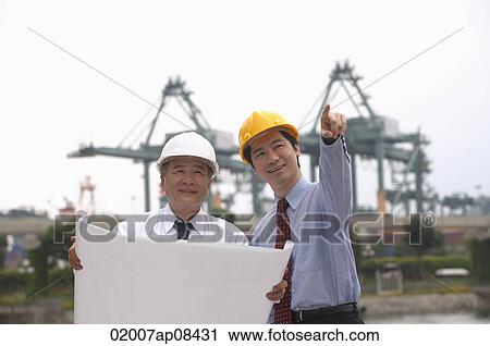 Men with helmets and blueprints View Large Photo Image Stock Image - Men with helmets and blueprints. Fotosearch