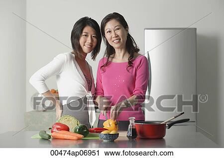 Mother and adult daughter in kitchen preparing a meal, looking at camera View Large Photo Image Stock Image - Mother and adult daughter in kitchen preparing a meal, looking at camera. Fotosearch