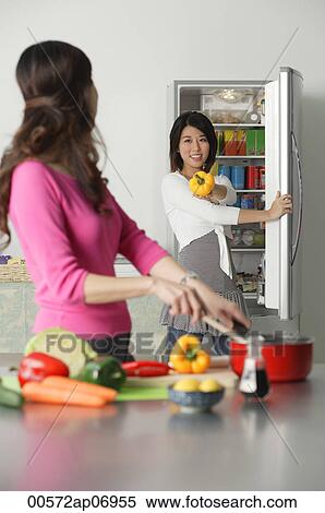 Mother and adult daughter in kitchen, daughter at refrigerator, holding bell pepper View Large Photo Image Stock Photography - Mother and adult daughter in kitchen, daughter at refrigerator, holding bell pepper. Fotosearch