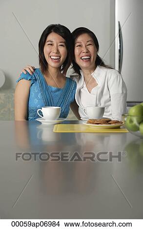 Mother and daughter at home, arms around each other, smiling View Large Photo Image Picture - Mother and daughter at home, arms around each other, smiling. Fotosearch