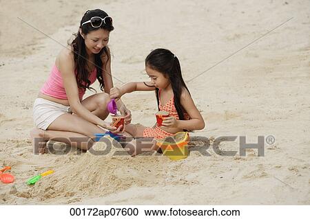 Mother and daughter building sand castle on beach View Large Photo Image Stock Image - Mother and daughter building sand castle on beach. Fotosearch