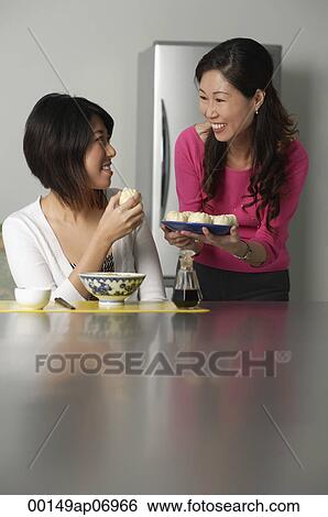 Mother and daughter in kitchen, older woman offering daughter a plate of Chinese buns View Large Photo Image Stock Photograph - Mother and daughter in kitchen, older woman offering daughter a plate of Chinese buns. Fotosearch