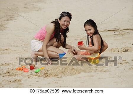 Mother and daughter on beach, building sand castle View Large Photo Image Stock Photo - Mother and daughter on beach, building sand castle. Fotosearch