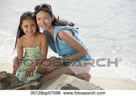Mother and daughter on beach by rocks View Large Photo Image Stock Photograph - Mother and daughter on beach by rocks. Fotosearch