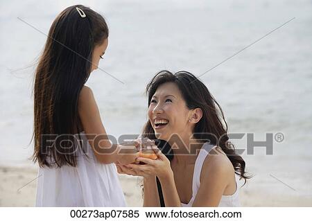 Mother and daughter on beach, daughter handing conk shell to mother, smiling View Large Photo Image Stock Photography - Mother and daughter on beach, daughter handing conk shell to mother, smiling. Fotosearch