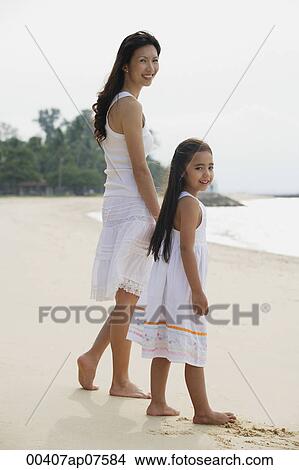 Mother and daughter standing on beach, wearing white dresses View Large Photo Image Picture - Mother and daughter standing on beach, wearing white dresses. Fotosearch