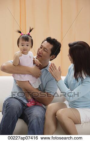 Mother and Father with baby girl, sitting on couch, happy View Large Photo Image Stock Photograph - Mother and Father with baby girl, sitting on couch, happy. Fotosearch