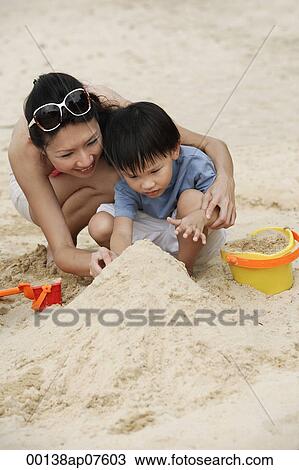 Mother and son building sand castle on beach View Large Photo Image Stock Image - Mother and son building sand castle on beach. Fotosearch