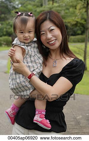 Mother carrying young daughter, smiling at camera View Large Photo Image Stock Image - Mother carrying young daughter, smiling at camera. Fotosearch