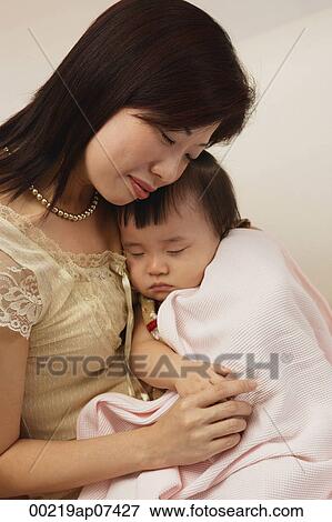 Mother holding baby girl in arms, baby girl wrapped up in blanket, peaceful View Large Photo Image Stock Photo - Mother holding baby girl in arms, baby girl wrapped up in blanket, peaceful. Fotosearch
