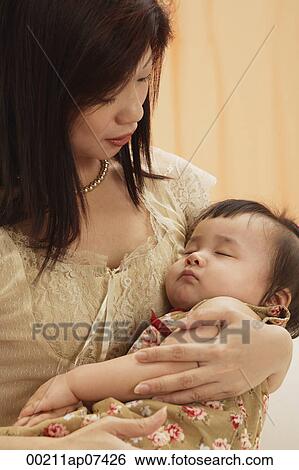 mother holding baby girl in arms, baby sleeping, mother looking at baby View Large Photo Image Stock Photograph - mother holding baby girl in arms, baby sleeping, mother looking at baby. Fotosearch