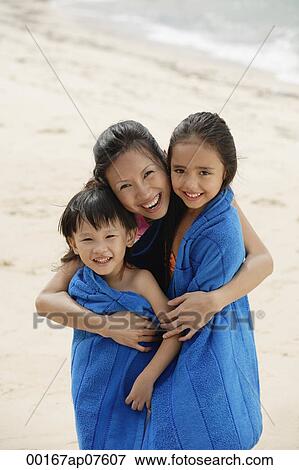 Mother on beach with son and daughter, mother hugging children and wrapping them in blue towel View Large Photo Image Stock Photo - Mother on beach with son and daughter, mother hugging children and wrapping them in blue towel. Fotosearch