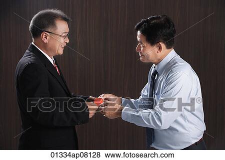 One man gives another a business card View Large Photo Image Stock Photo - One man gives another a business card. Fotosearch