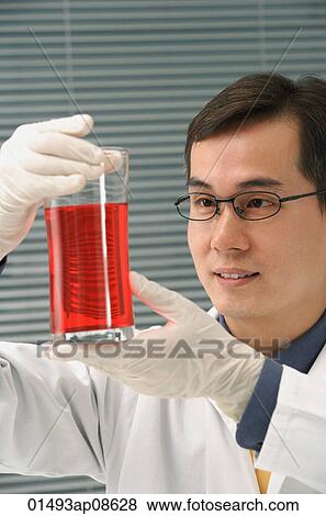 Scientist examining container of fluid View Large Photo Image Stock Photo - Scientist examining container of fluid. Fotosearch