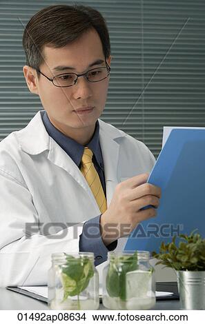 Scientist examining jar with plant samples View Large Photo Image Picture - Scientist examining jar with plant samples. Fotosearch
