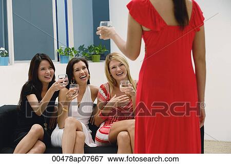 Three women sitting on couch and toasting glasses to woman standing View Large Photo Image Stock Photo - Three women sitting on couch and toasting glasses to woman standing. Fotosearch