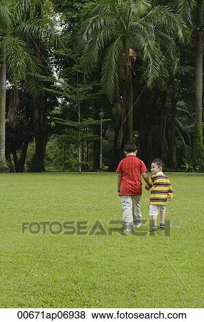 Two brothers walking in park, one looking over shoulder View Large Photo Image Stock Photo - Two brothers walking in park, one looking over shoulder. Fotosearch
