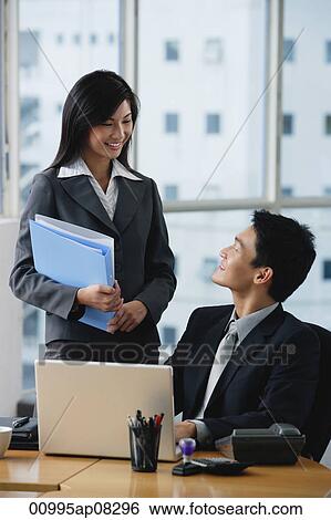 Stock Photograph - Two colleagues smile at each other. Fotosearch