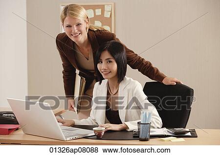 Two female colleagues smile at the camera together View Large Photo Image Stock Photo - Two female colleagues smile at the camera together. Fotosearch