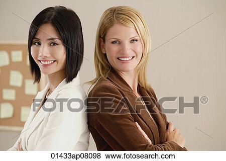Two female colleagues smile at the camera together View Large Photo Image Stock Photo - Two female colleagues smile at the camera together. Fotosearch