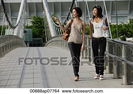Two friends walk across a bridge together View Large Photo Image Picture - Two friends walk across a bridge together. Fotosearch