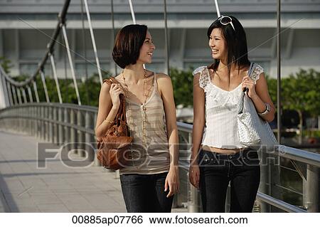 Two friends walk across a bridge together View Large Photo Image Stock Photograph - Two friends walk across a bridge together. Fotosearch