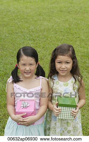 Two girls with gift boxes, standing side by side, smiling at camera View Large Photo Image Stock Image - Two girls with gift boxes, standing side by side, smiling at camera. Fotosearch